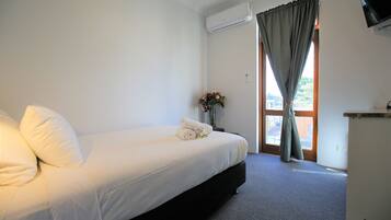 A hotel room with a bed, a desk, and a window with curtains.