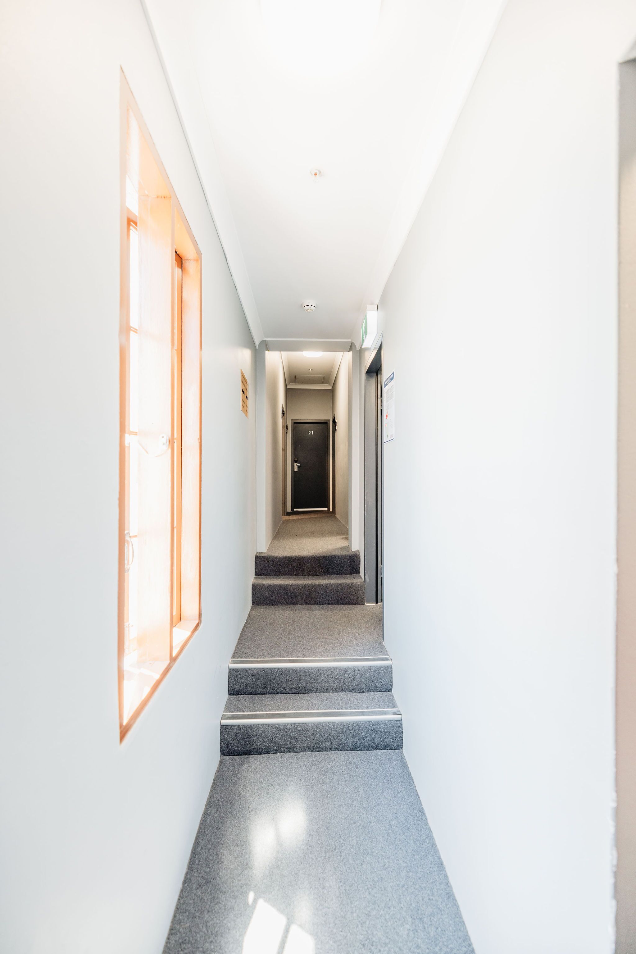 Ein moderner Hotelkorridor mit einer Treppe, die zu einer Tür mit der Nummer 21 führt.