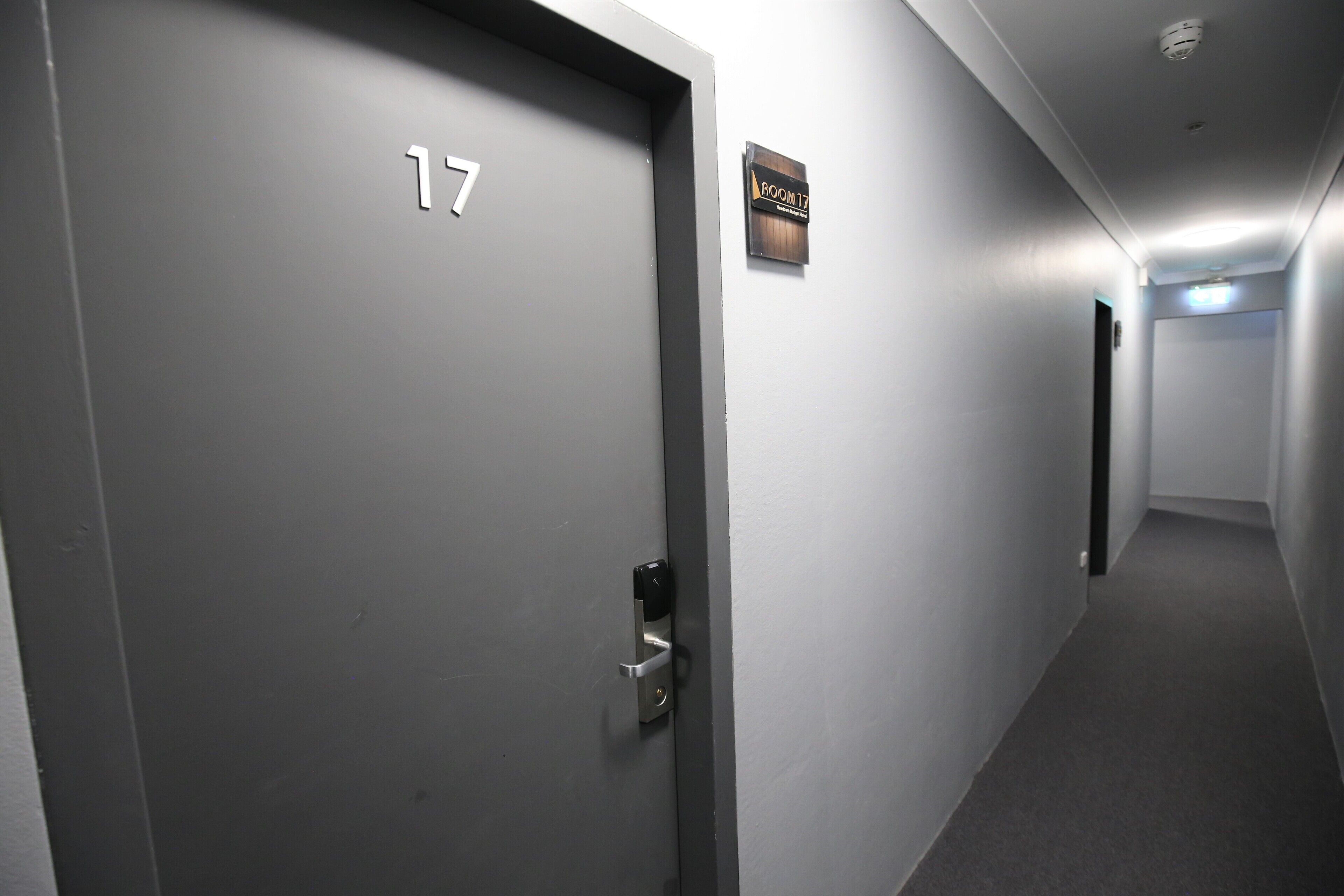 Un pasillo con una puerta que tiene la etiqueta '17' y un cartel que indica 'Habitación 17'.