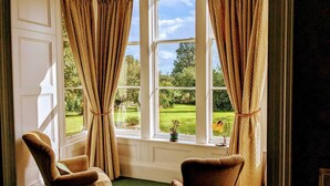 A room with two armchairs, a large window with curtains, and a view of a garden. - The Gables (Berwick-upon-Tweed)