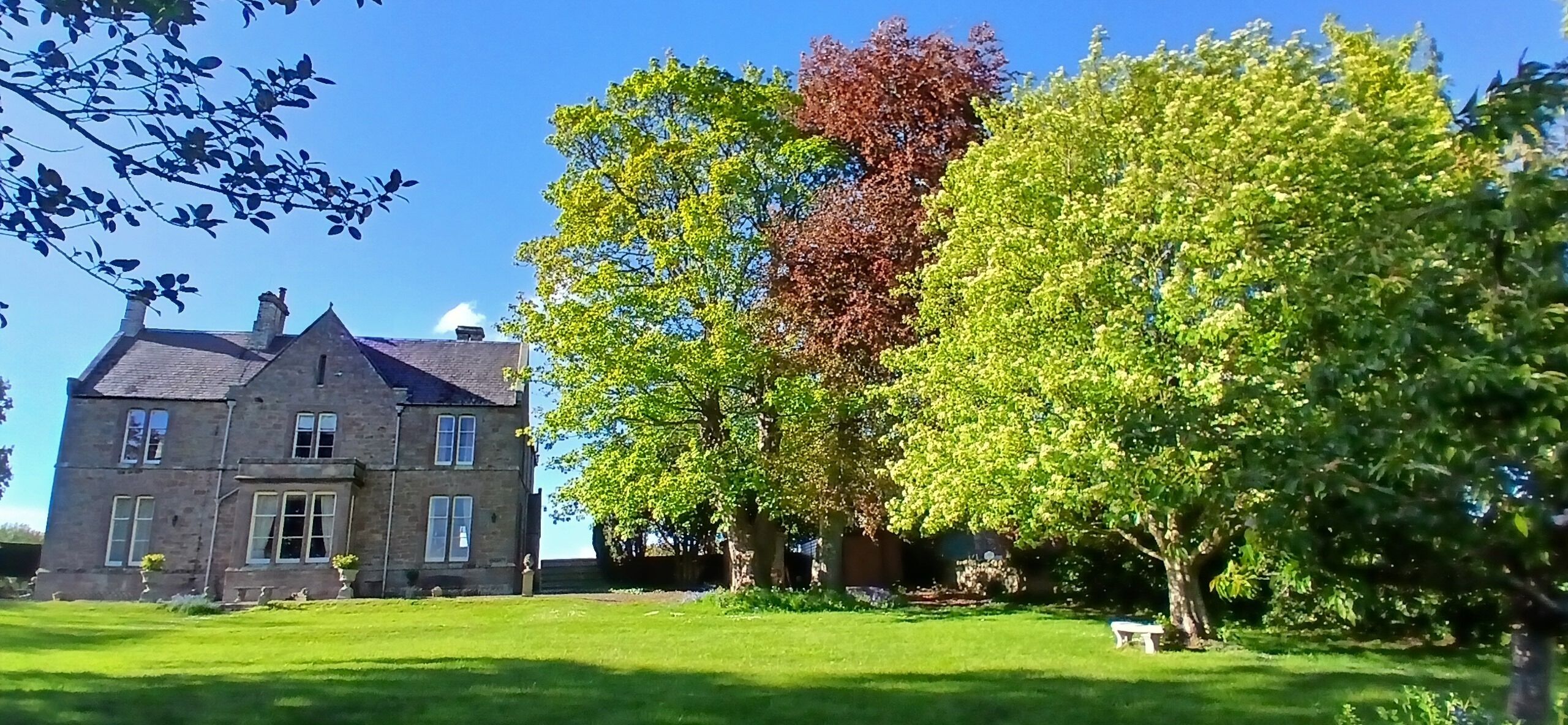 A large stone building with multiple windows and a well-maintained lawn.