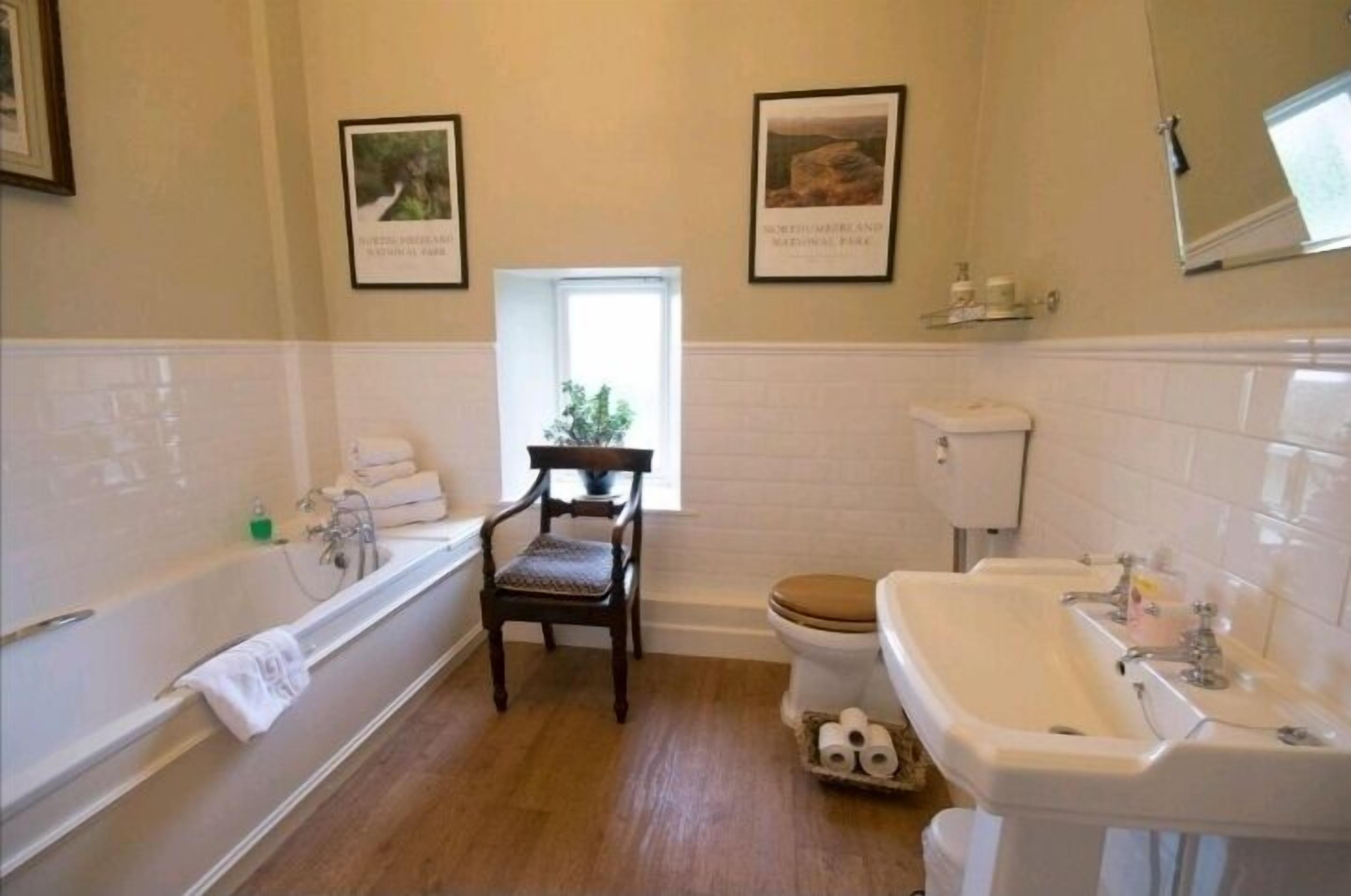Un baño con bañera, lavamanos, inodoro y una silla.