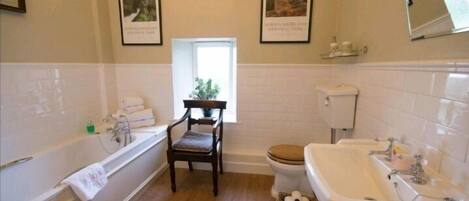 Un baño con bañera, lavamanos, inodoro y una silla.