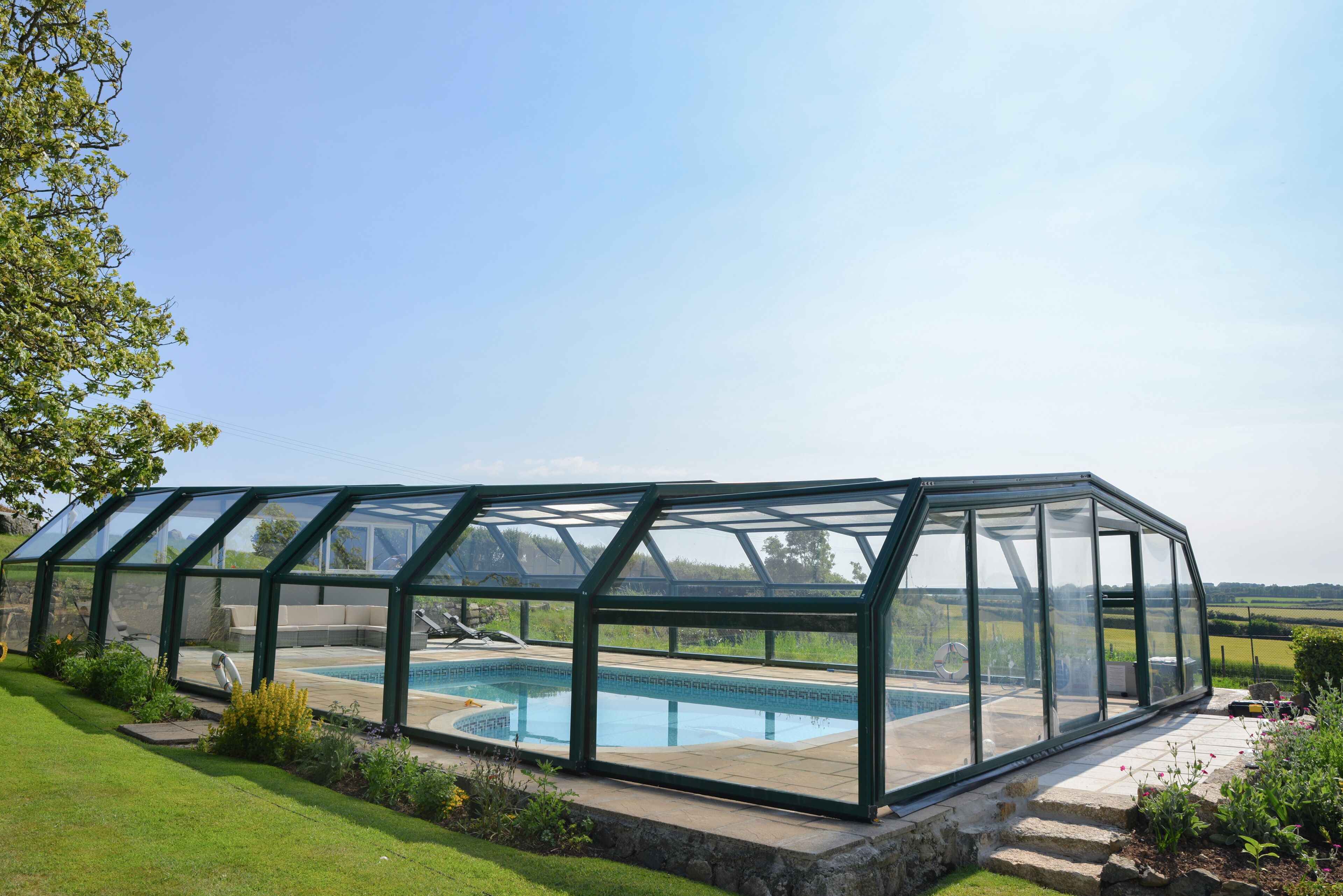 A glass-enclosed swimming pool with a built-in seating area and a view of the surrounding landscape.