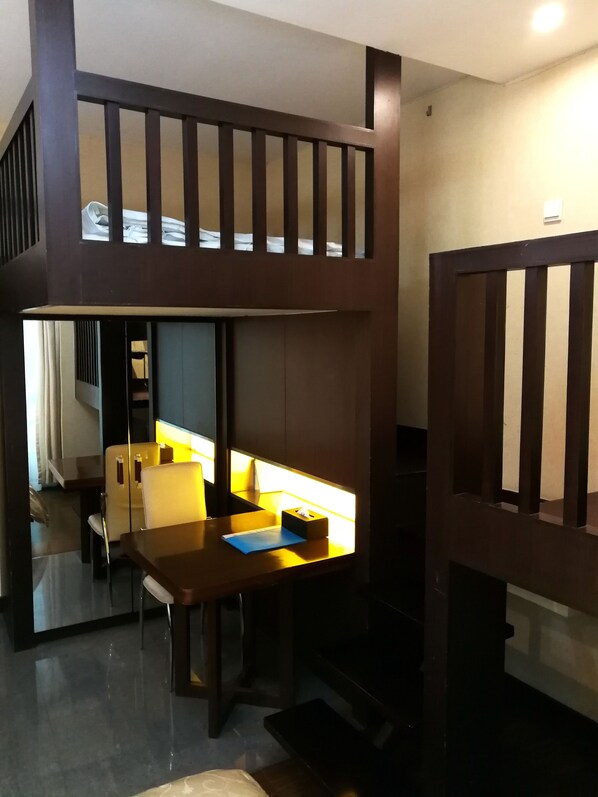 A room with a wooden desk, a chair, a small table, and a bed.