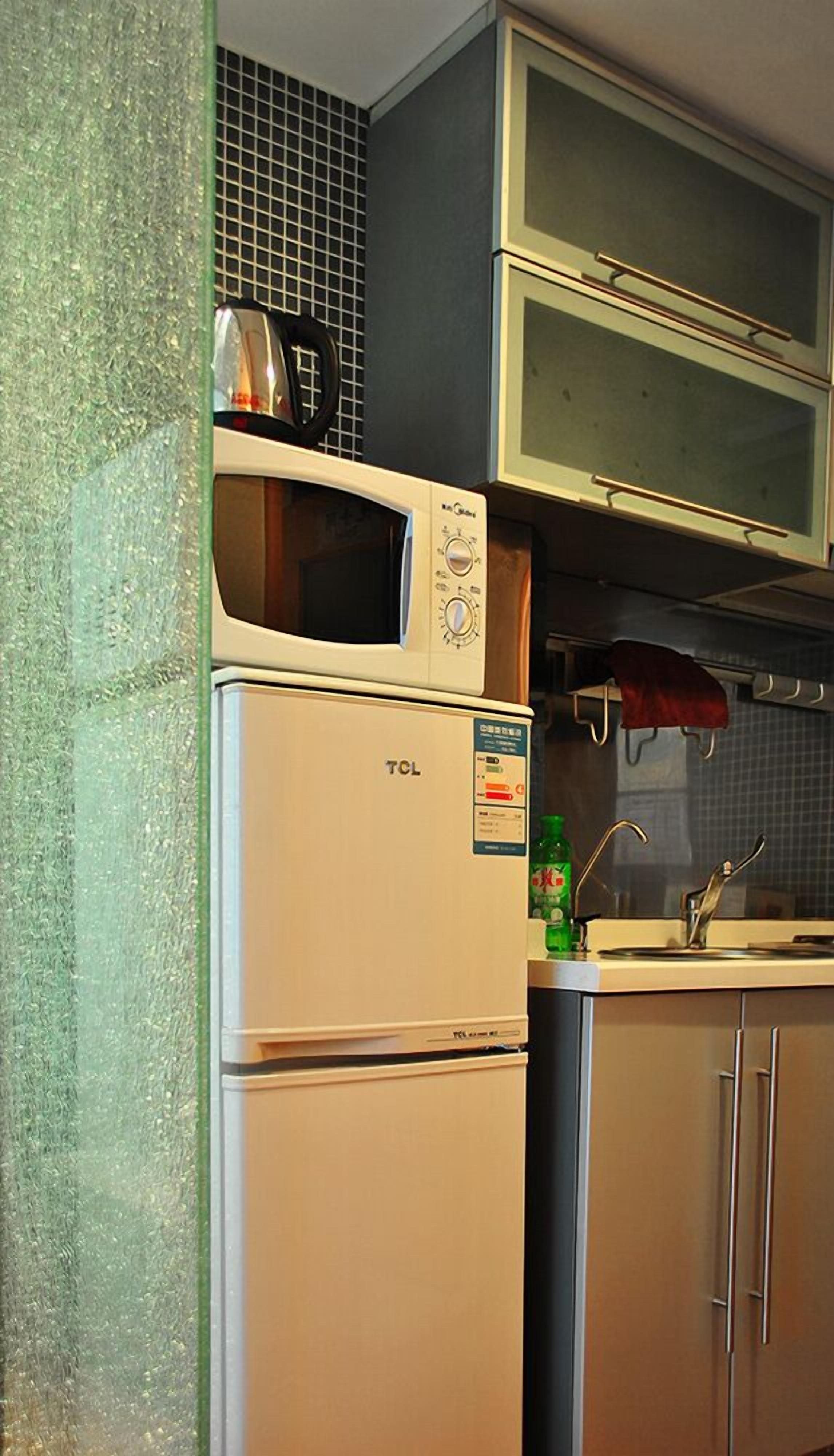 A kitchen with a TCL refrigerator, a microwave, and a sink with a faucet.