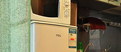 A kitchen with a TCL refrigerator, a microwave, and a sink with a faucet.