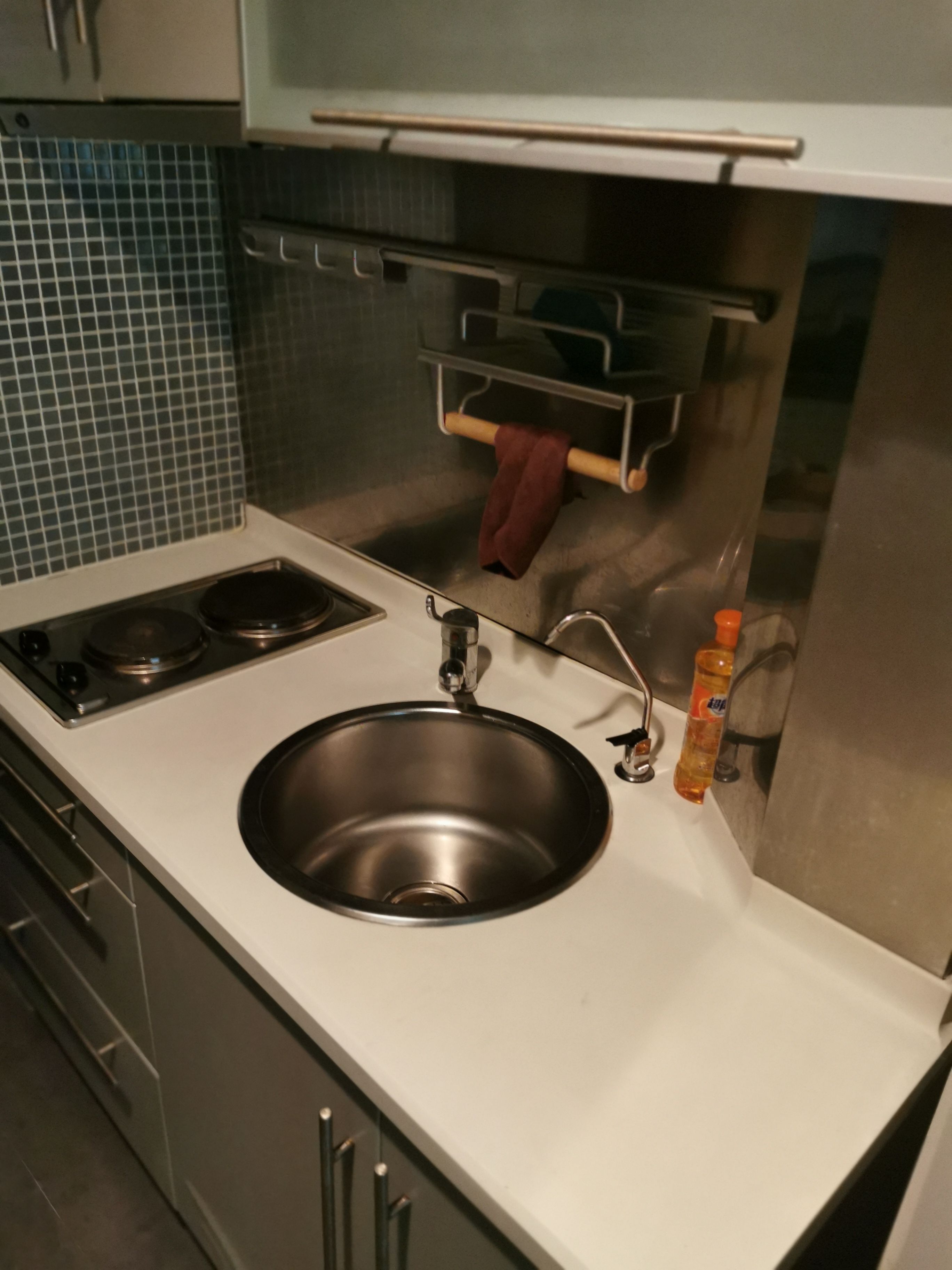 A kitchen with a stainless steel sink, a stove, and a towel rack.