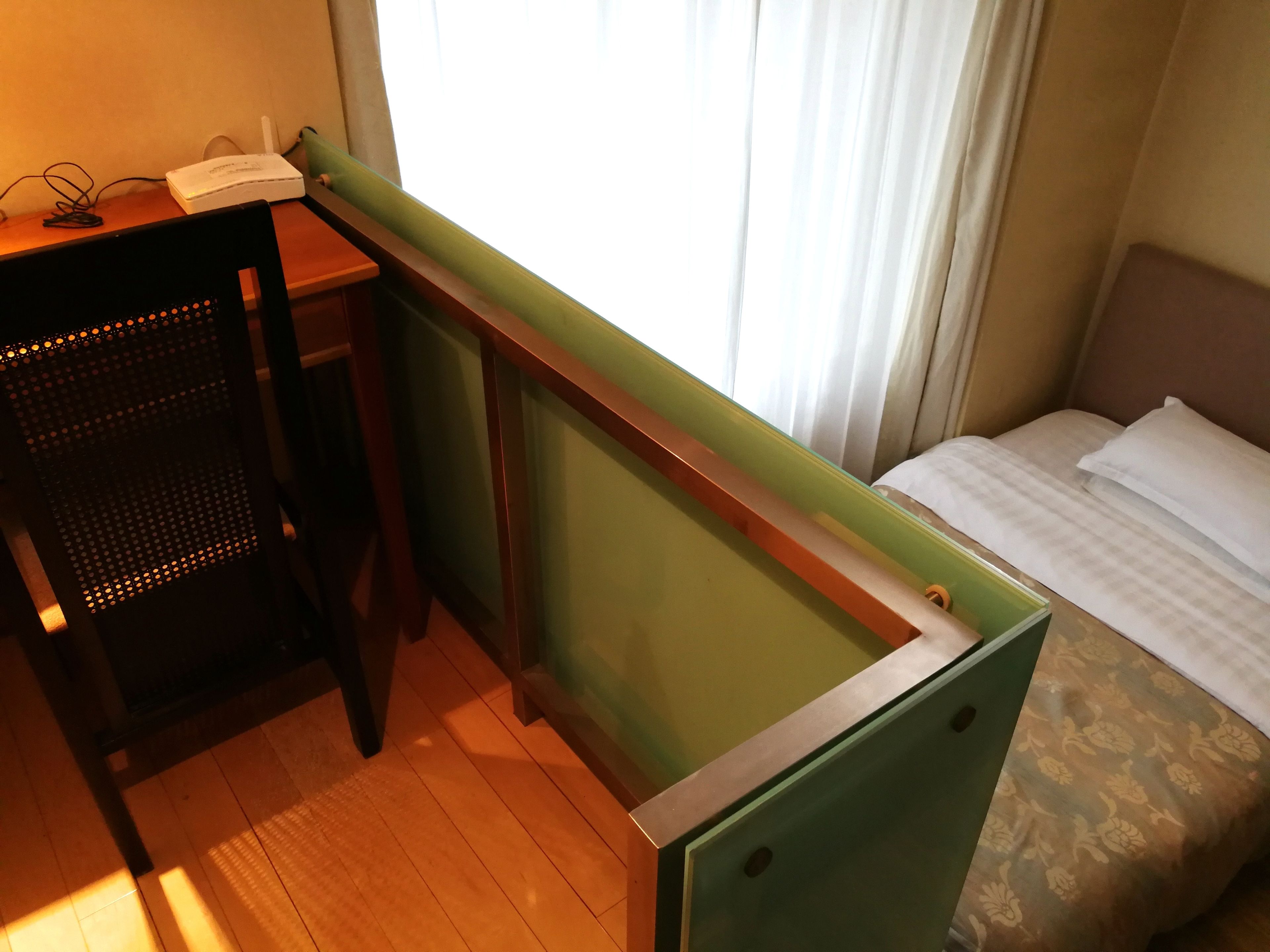 A compact hotel room with a desk, chair, and a bed.