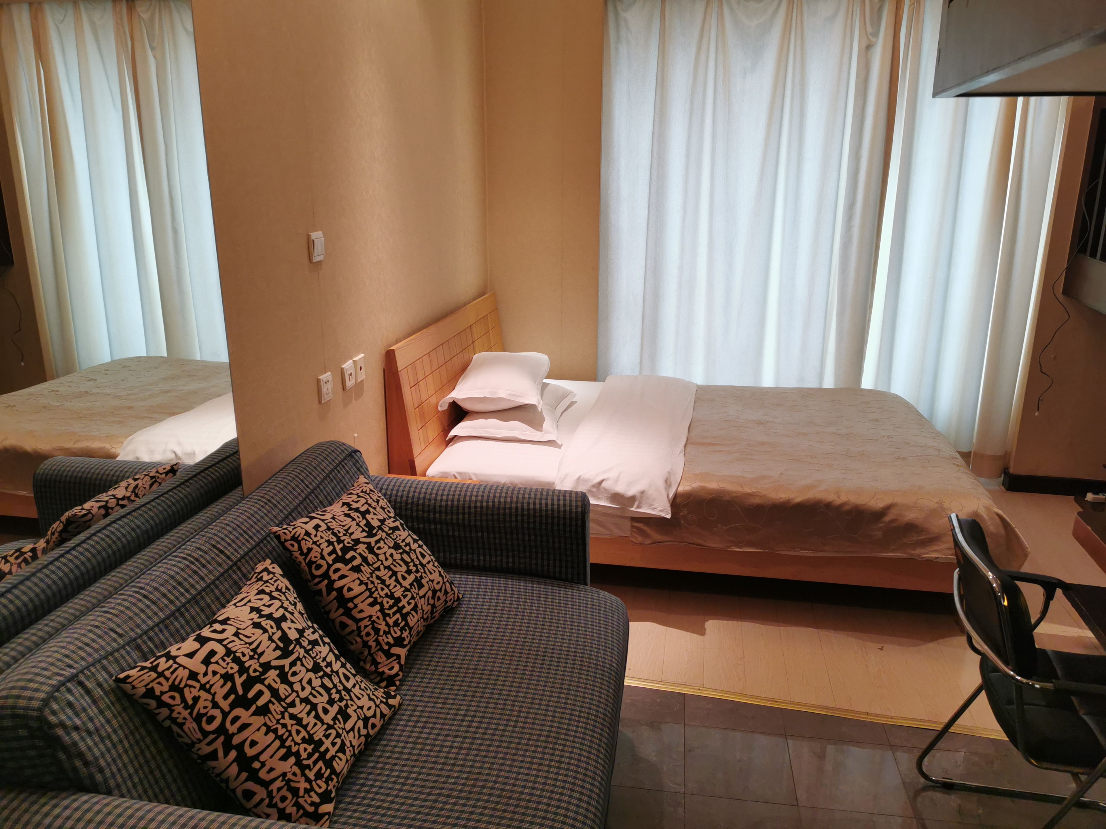 A hotel room with two beds, a sofa, and a chair.