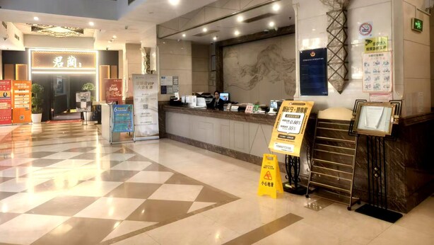 Un espace d’accueil d’hôtel comprenant un comptoir d’enregistrement, un écran numérique et un bureau de réception.