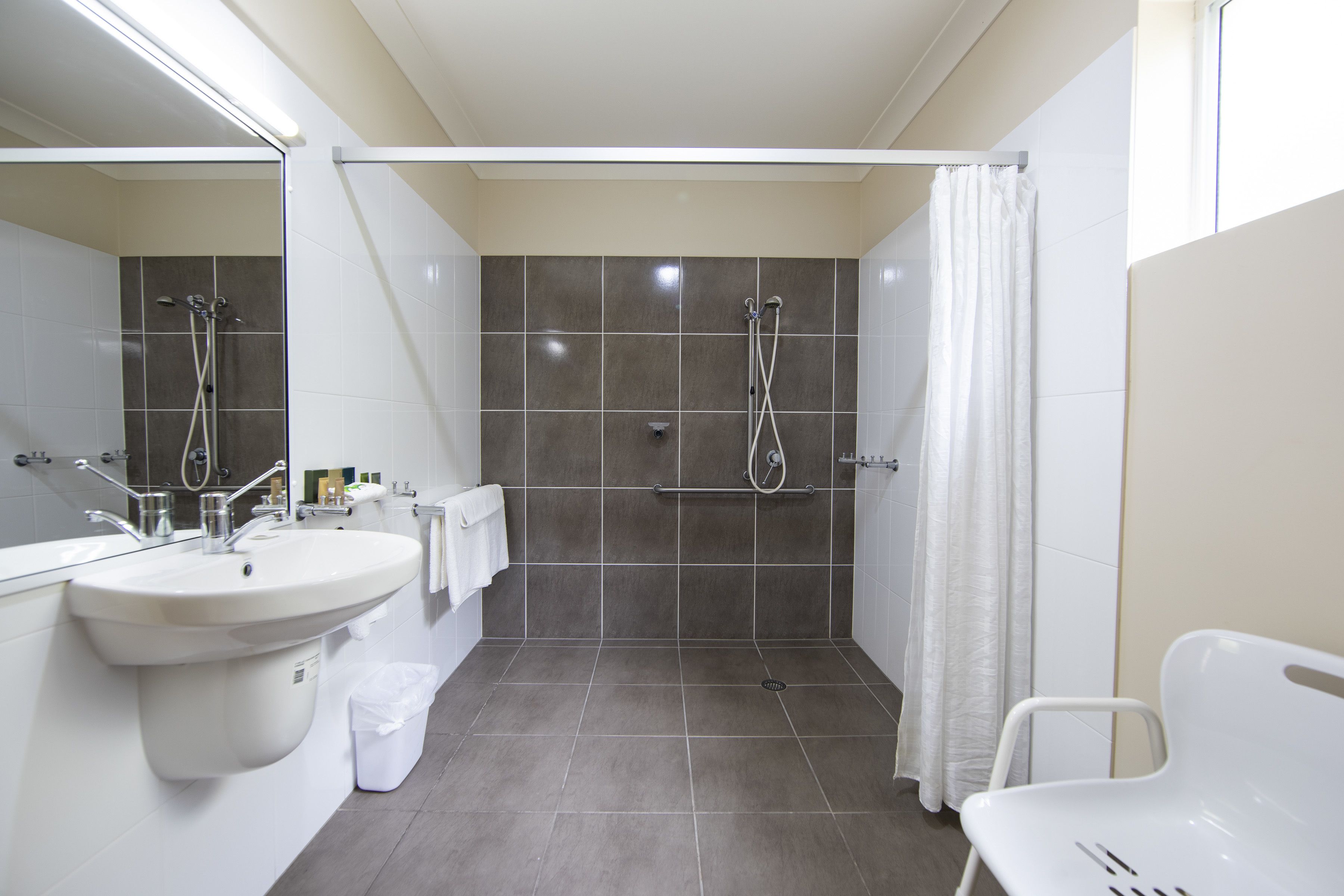 Ein modernes Badezimmer mit Waschbecken, Spiegel, Dusche und Toilette.