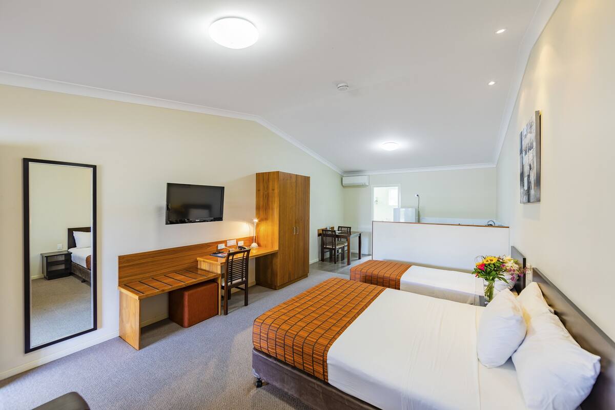 A hotel room with a bed, desk, chair, and a TV.