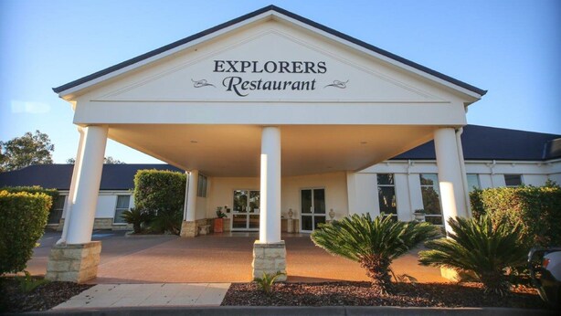 El exterior del Restaurante Explorers, con una entrada cubierta, columnas y cielo despejado.