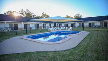 Een buitenzwembad, ligstoelen bij het zwembad