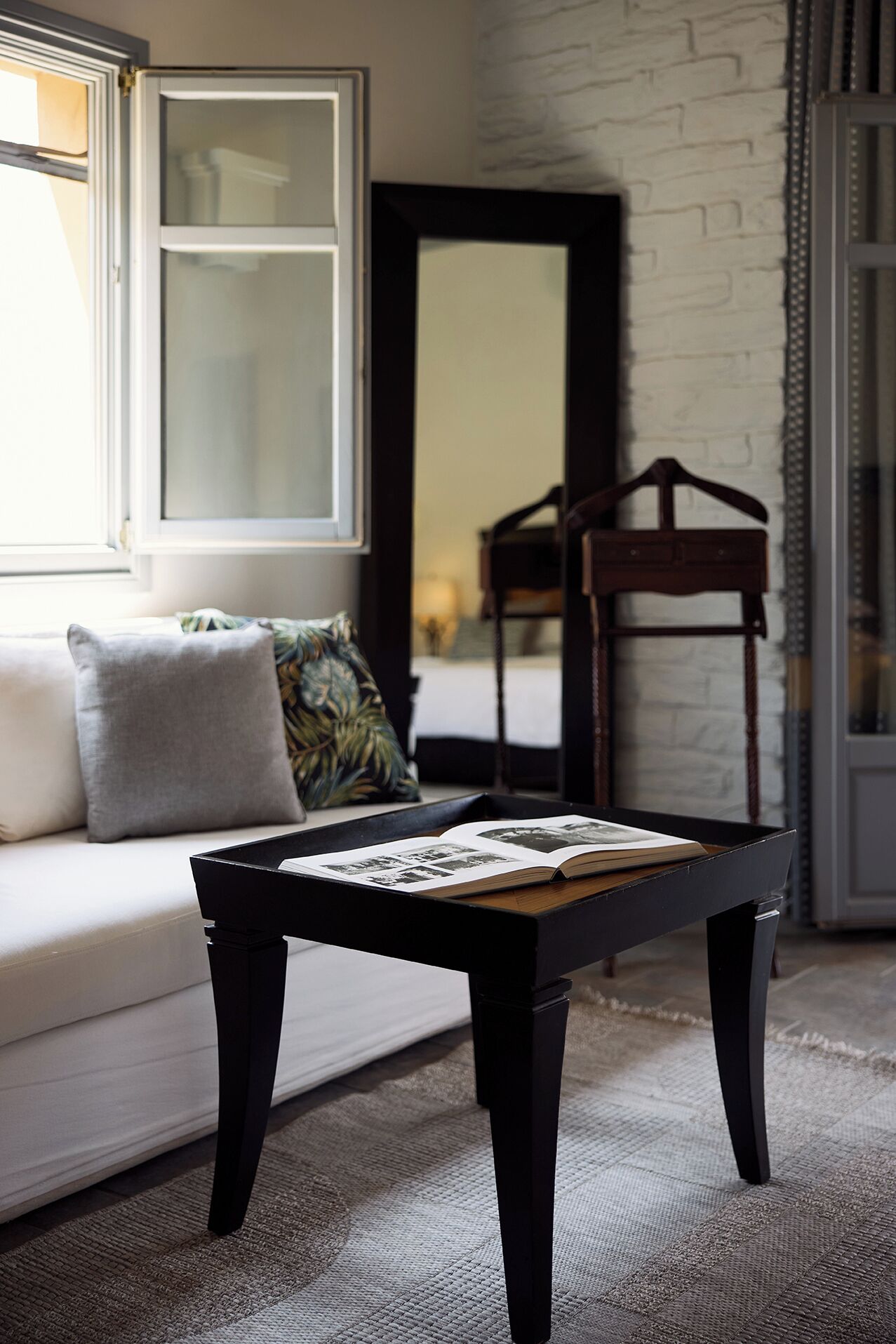 A modern living room with a white sofa, a black coffee table, and a mirror on the wall.