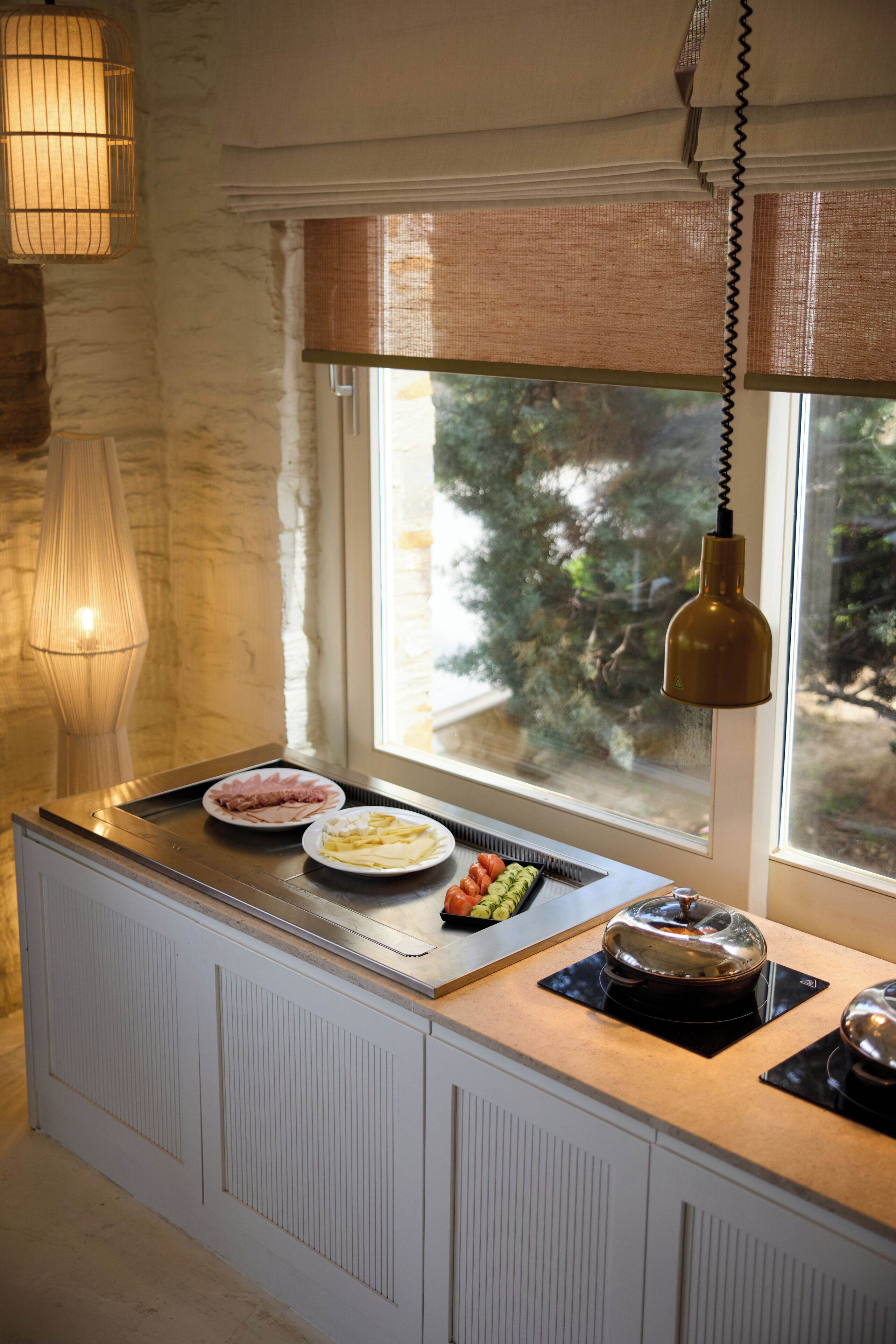 Una cocina con ventana, lámpara y una mesa de buffet.