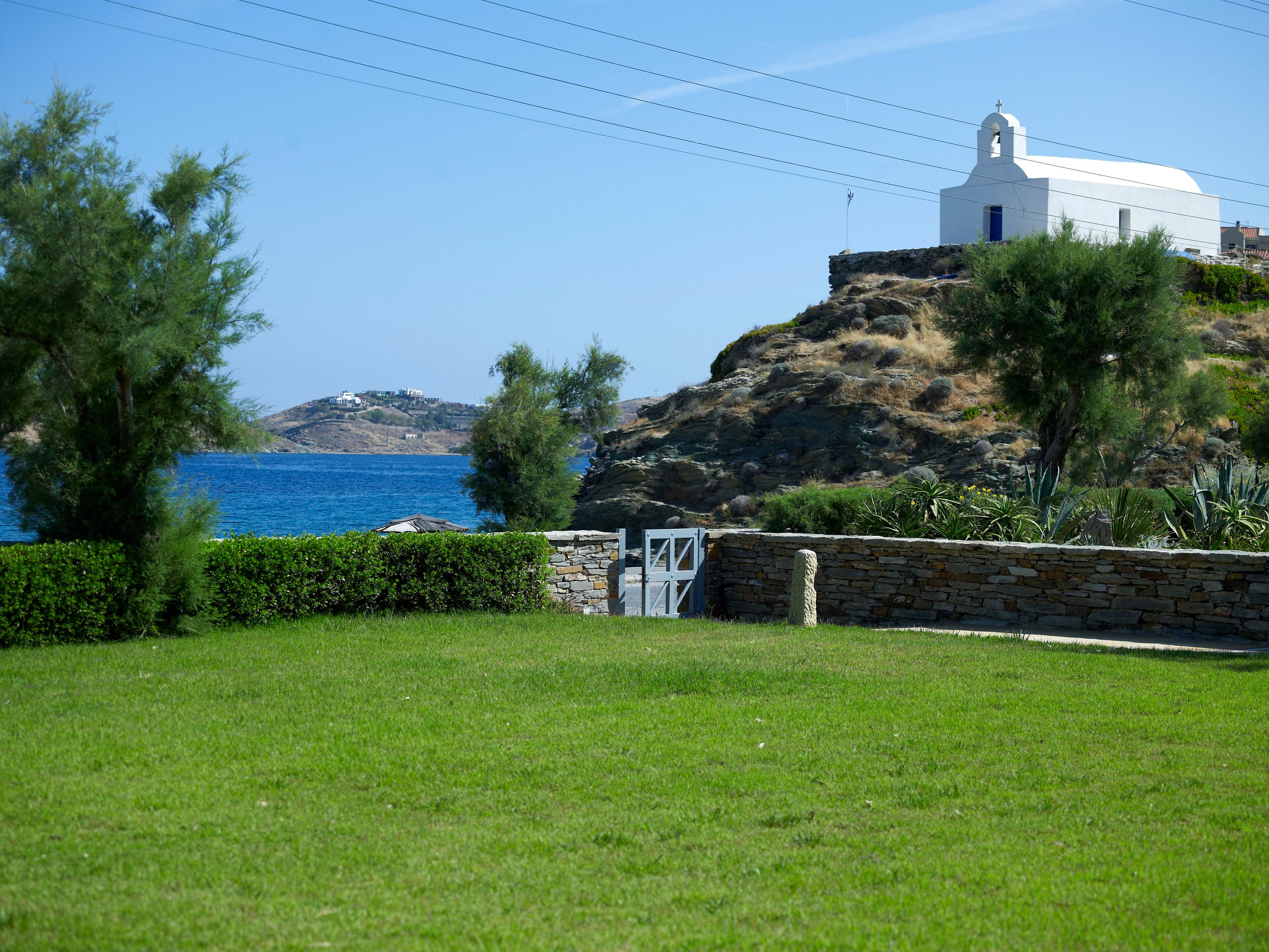Un edificio blanco con una cúpula y un campanario, situado en una colina con vistas al mar.