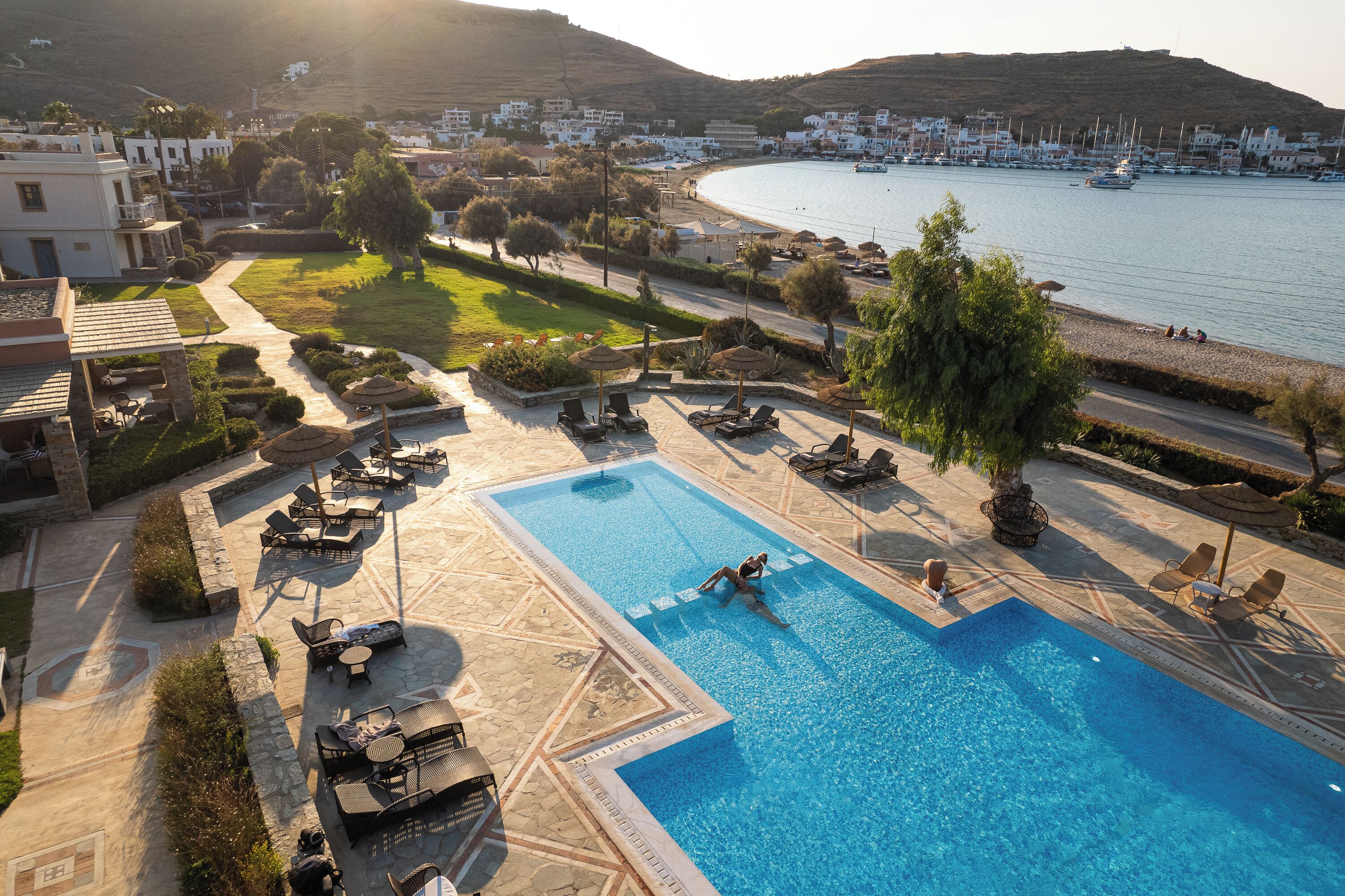 A swimming pool with lounge chairs and a view of the sea.