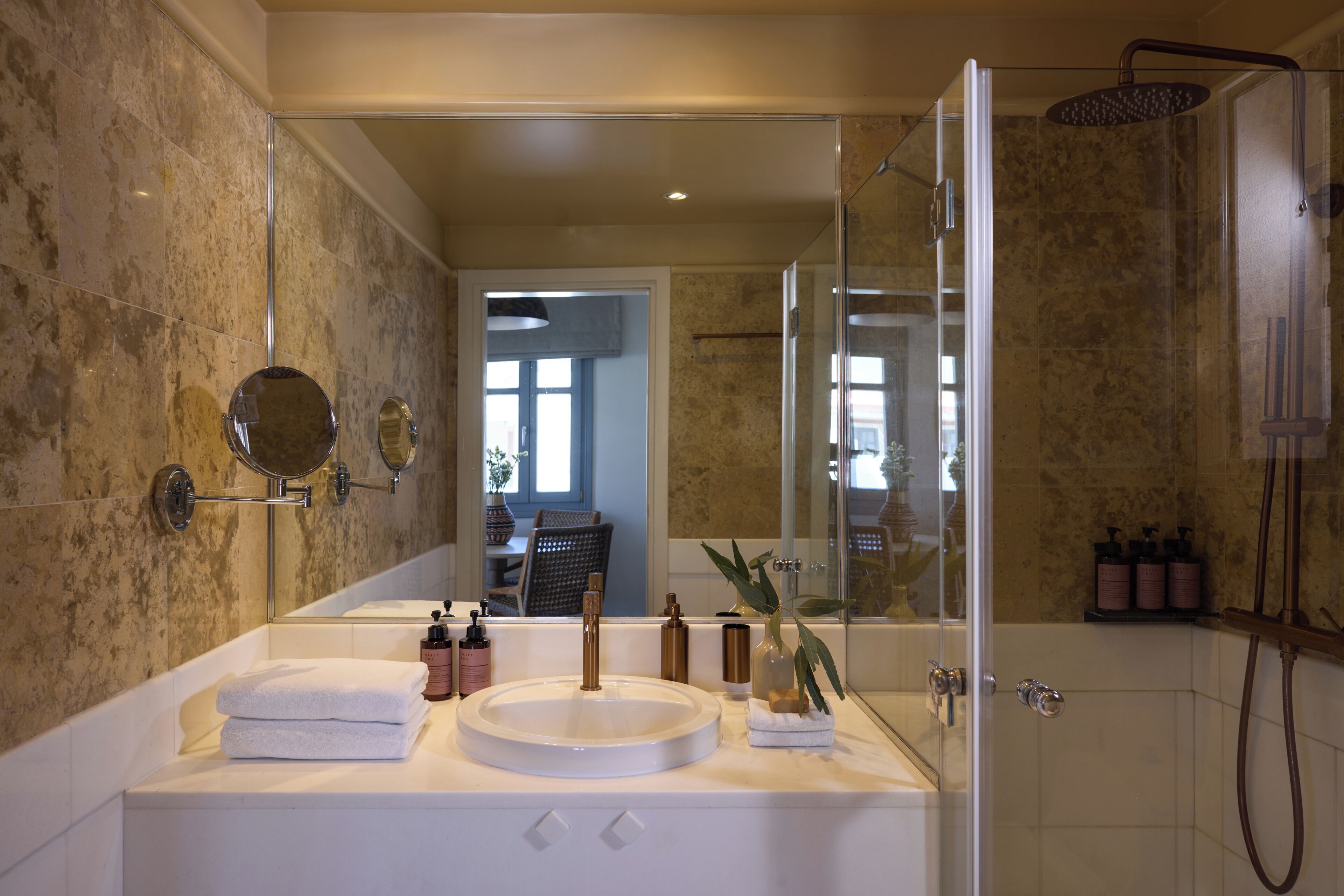 A modern bathroom with a glass-enclosed shower, a round sink, and a large mirror.