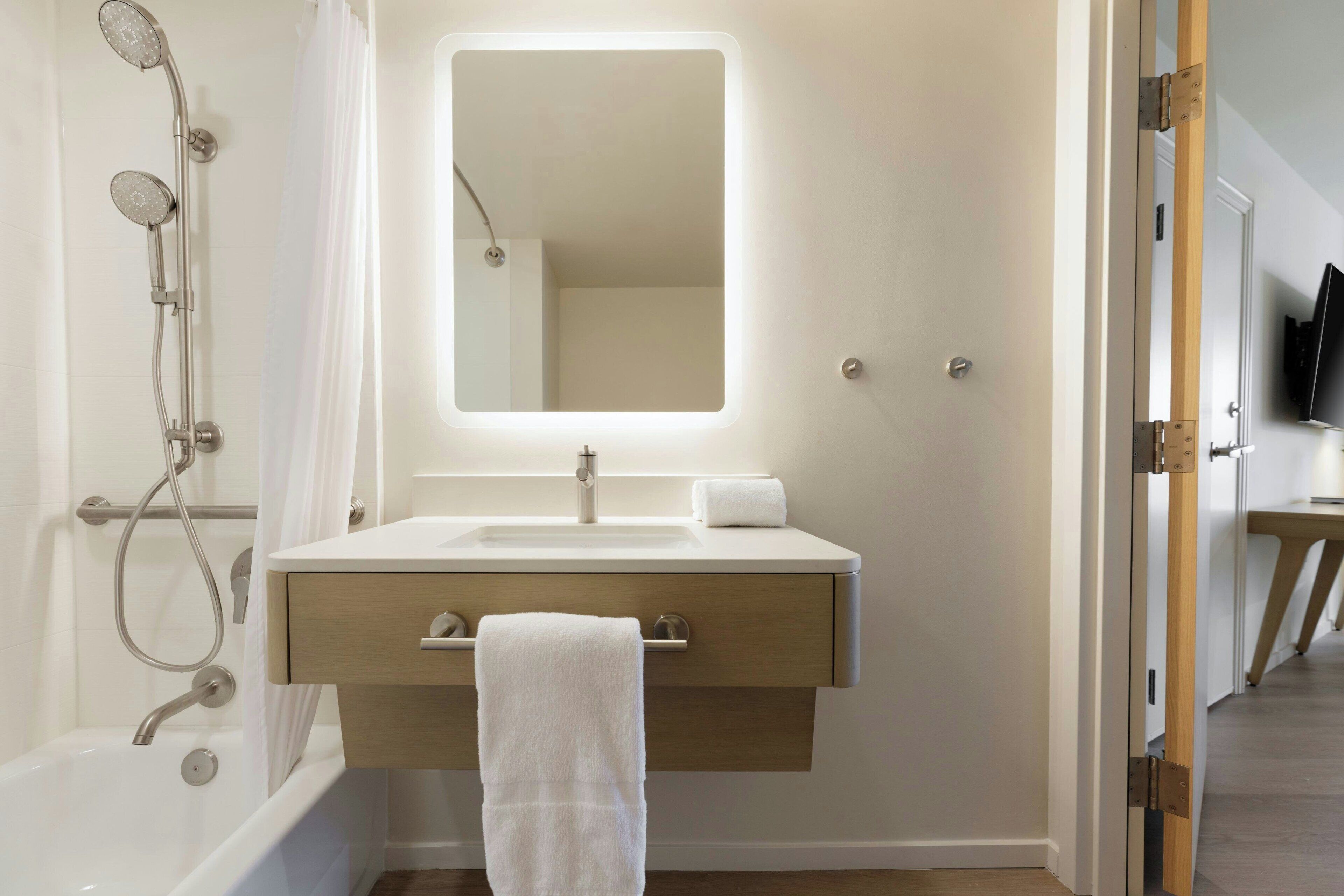 A modern bathroom with a bathtub, a sink, a mirror, and a showerhead.