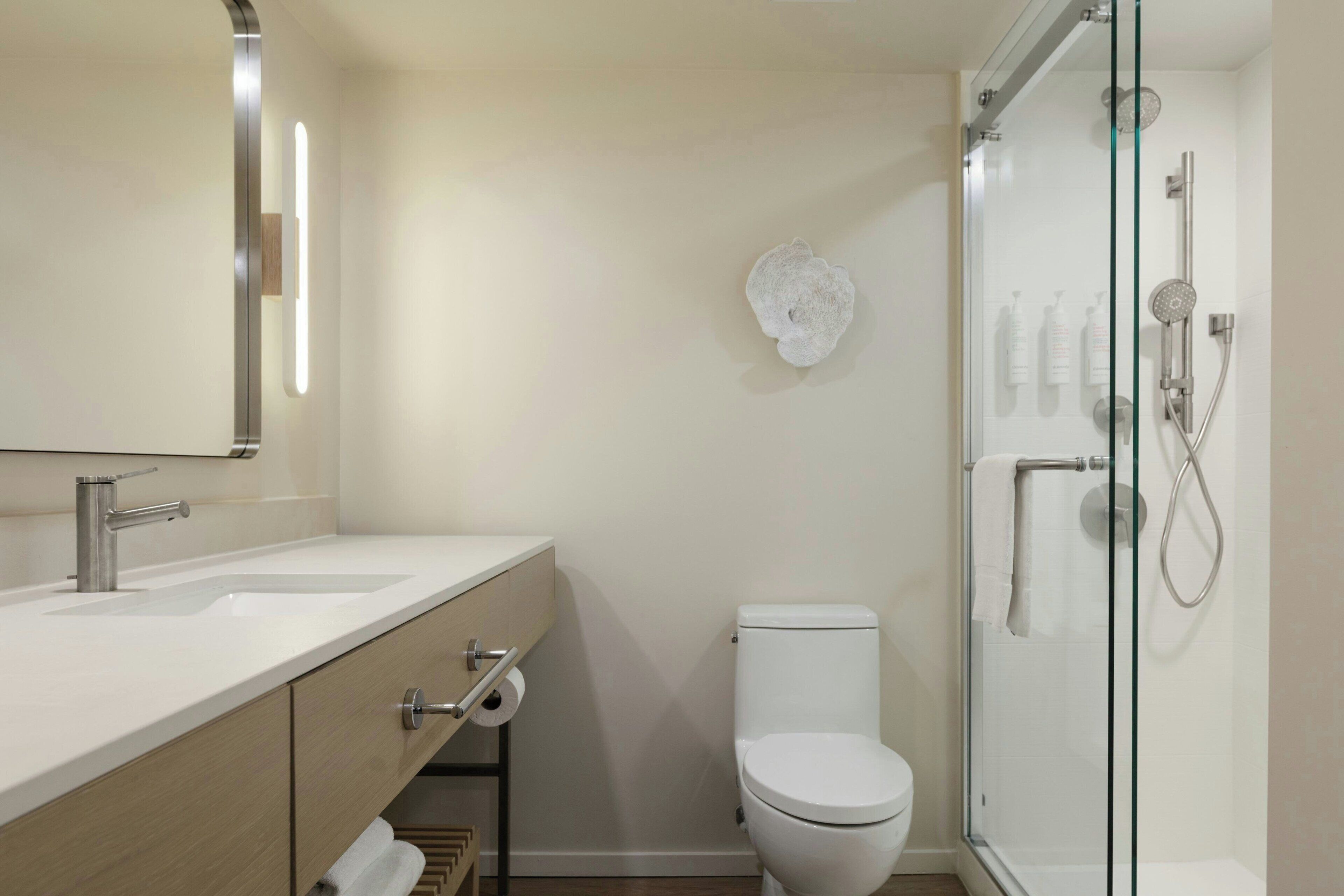 A modern bathroom with a glass-enclosed shower, a white toilet, and a vanity with a mirror and sink.
