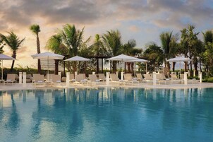 Una piscina al aire libre, camas de piscina con cargo, sombrillas