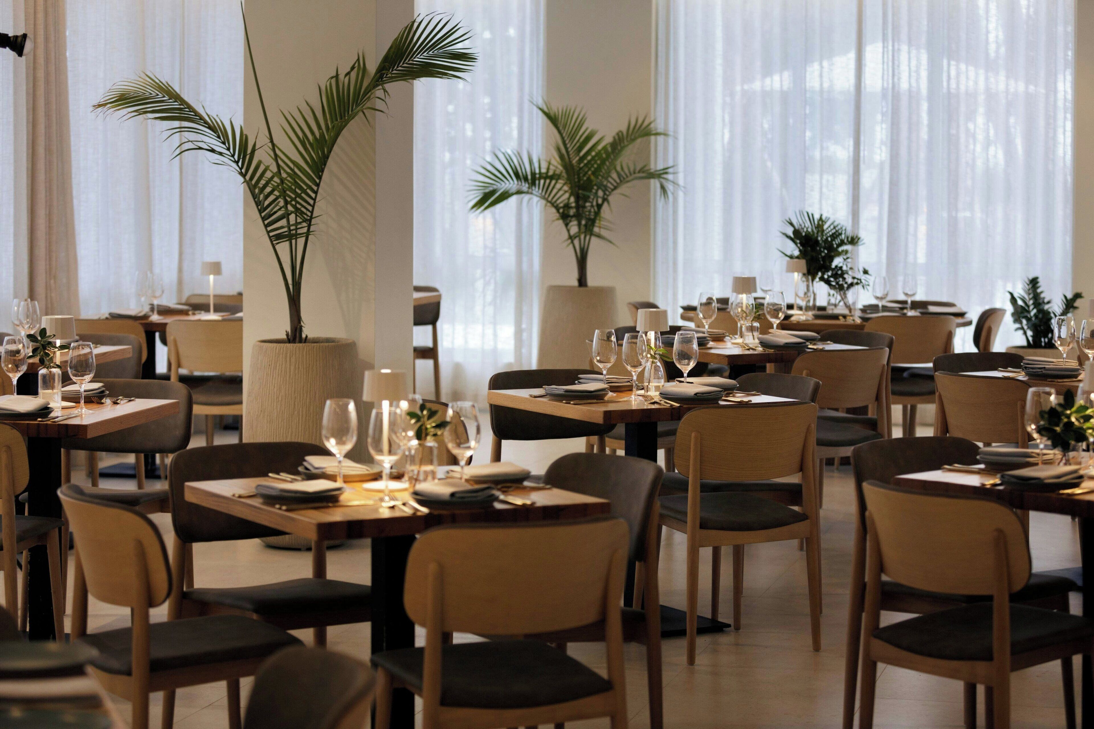 A restaurant with multiple tables set for dining, each with chairs and table settings.