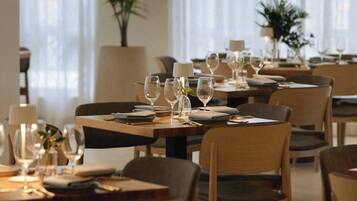A restaurant with tables set for dining, chairs, and potted plants.