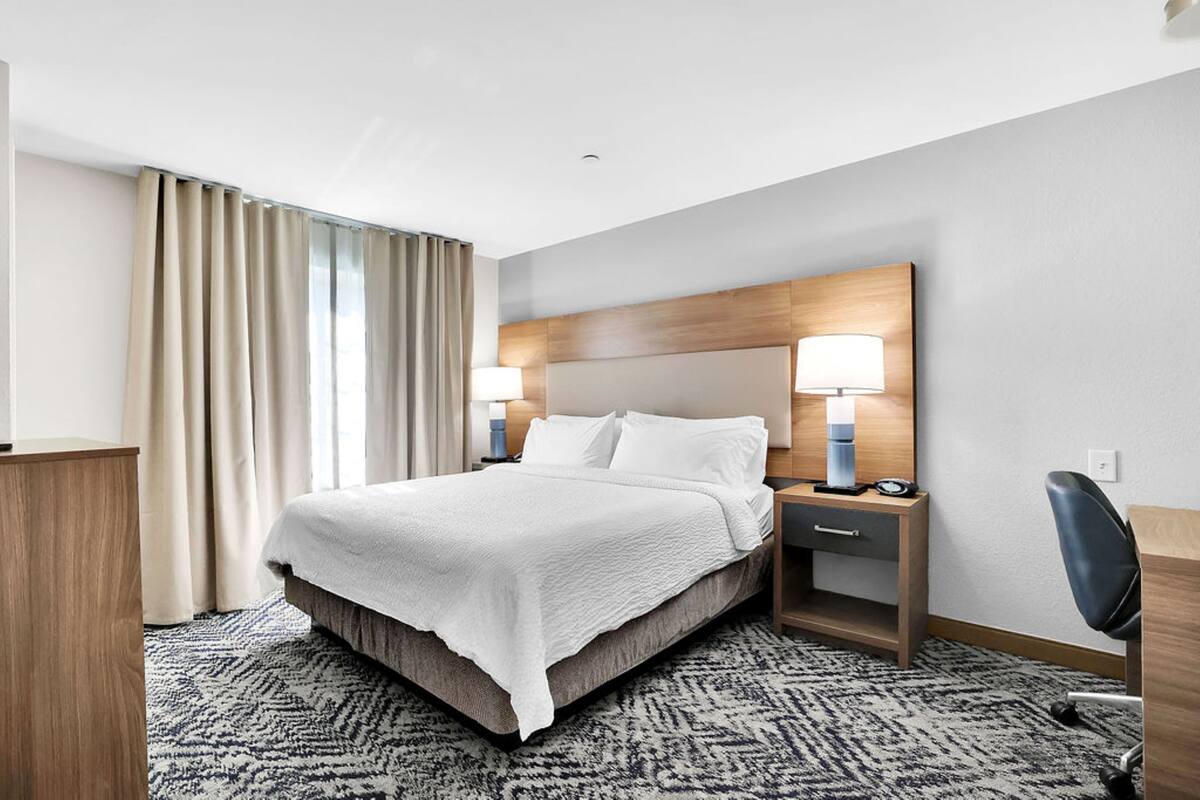 Une chambre d’hôtel avec un lit, des tables de chevet, un bureau et une chaise.