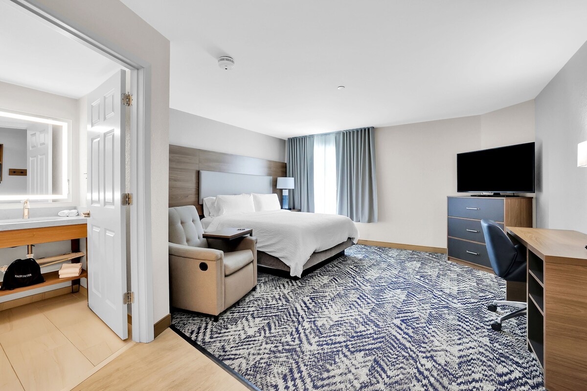 A modern hotel room with a bed, desk, chair, and a television.