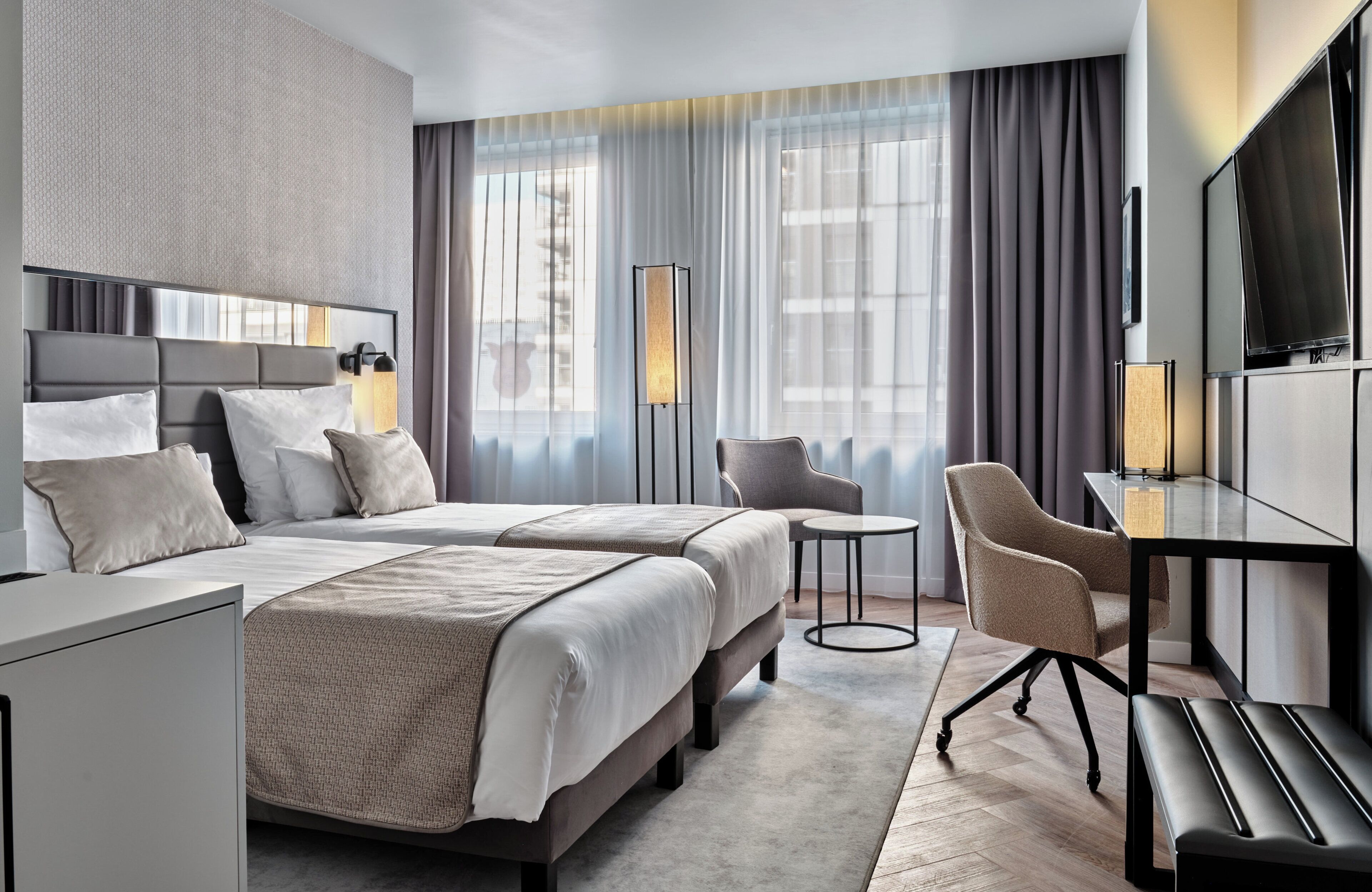 A hotel room with a double bed, a desk, a chair, and a TV.
