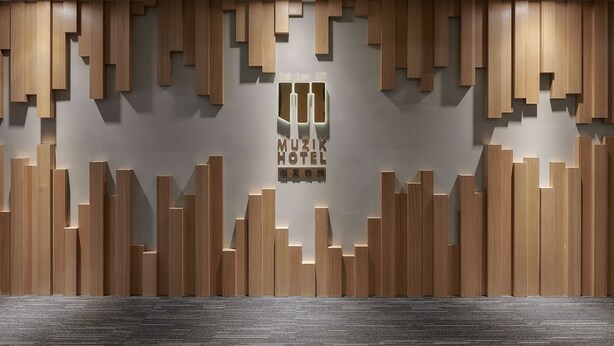 Un mur orné d’un motif géométrique composé de panneaux de bois et d’une enseigne indiquant « HÔTEL MUSICAL ».