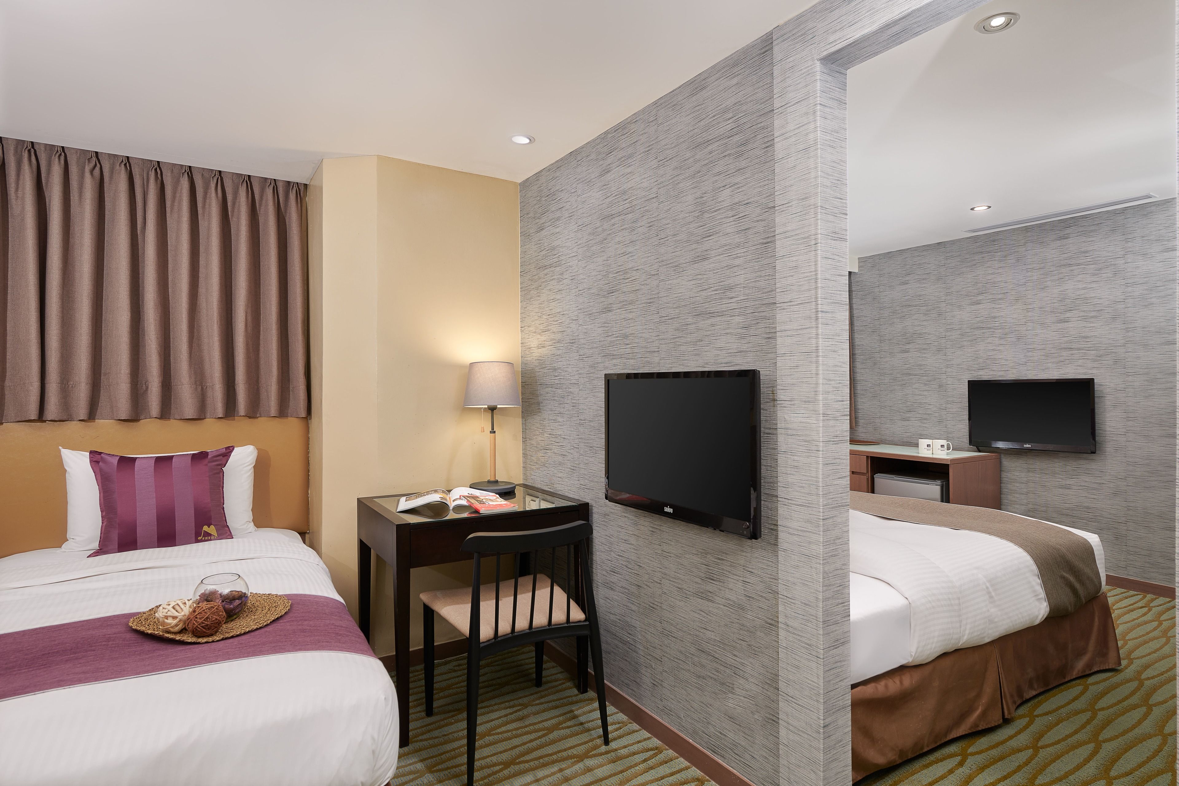 Une chambre d’hôtel avec deux lits, un bureau avec une lampe, un téléviseur à écran plat et un miroir.