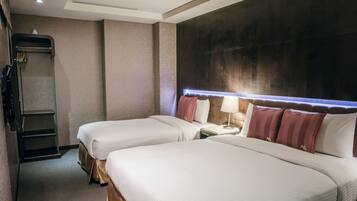 A hotel room with two beds, a bedside table with a lamp, a wardrobe, and a large window with a view.