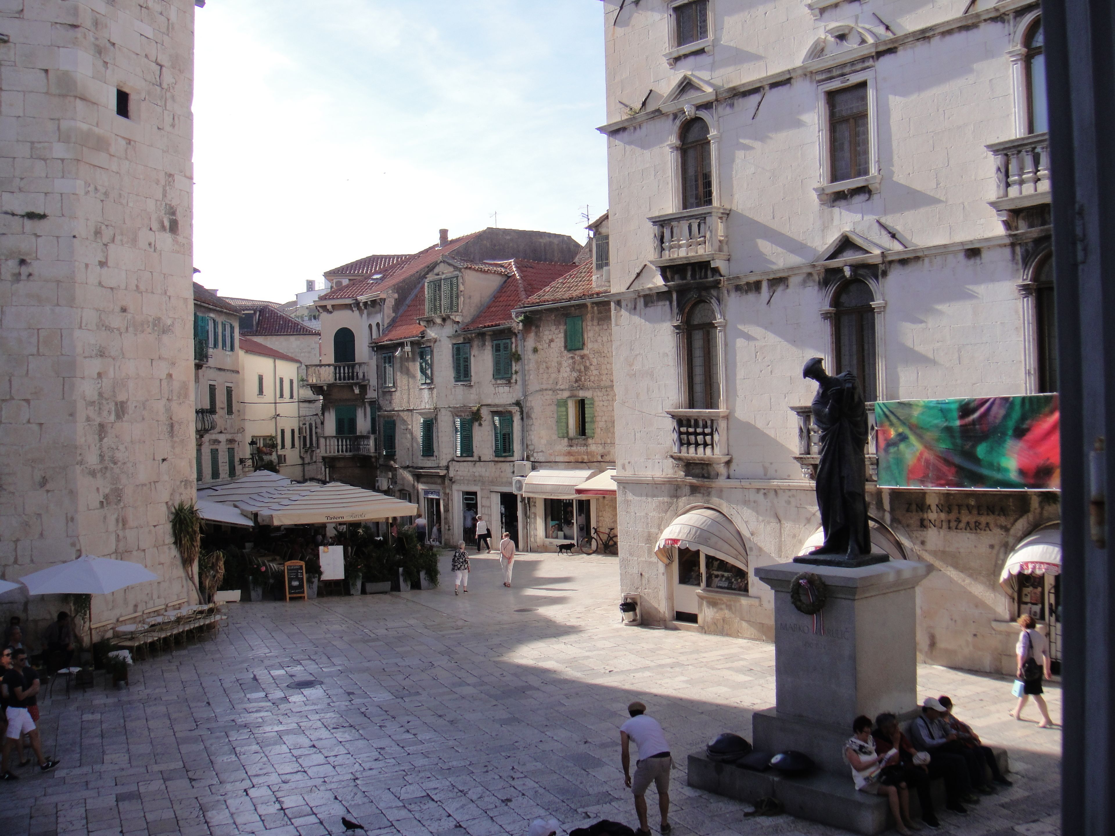 A historic square with cobblestone pavement, traditional buildings, and a statue.