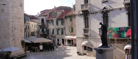 A historic square with cobblestone pavement, traditional buildings, and a statue.