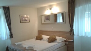 A neatly made bed with a wooden headboard, a bedside table, and a wall-mounted mirror. - B&B Central Palace Heritage (Split)