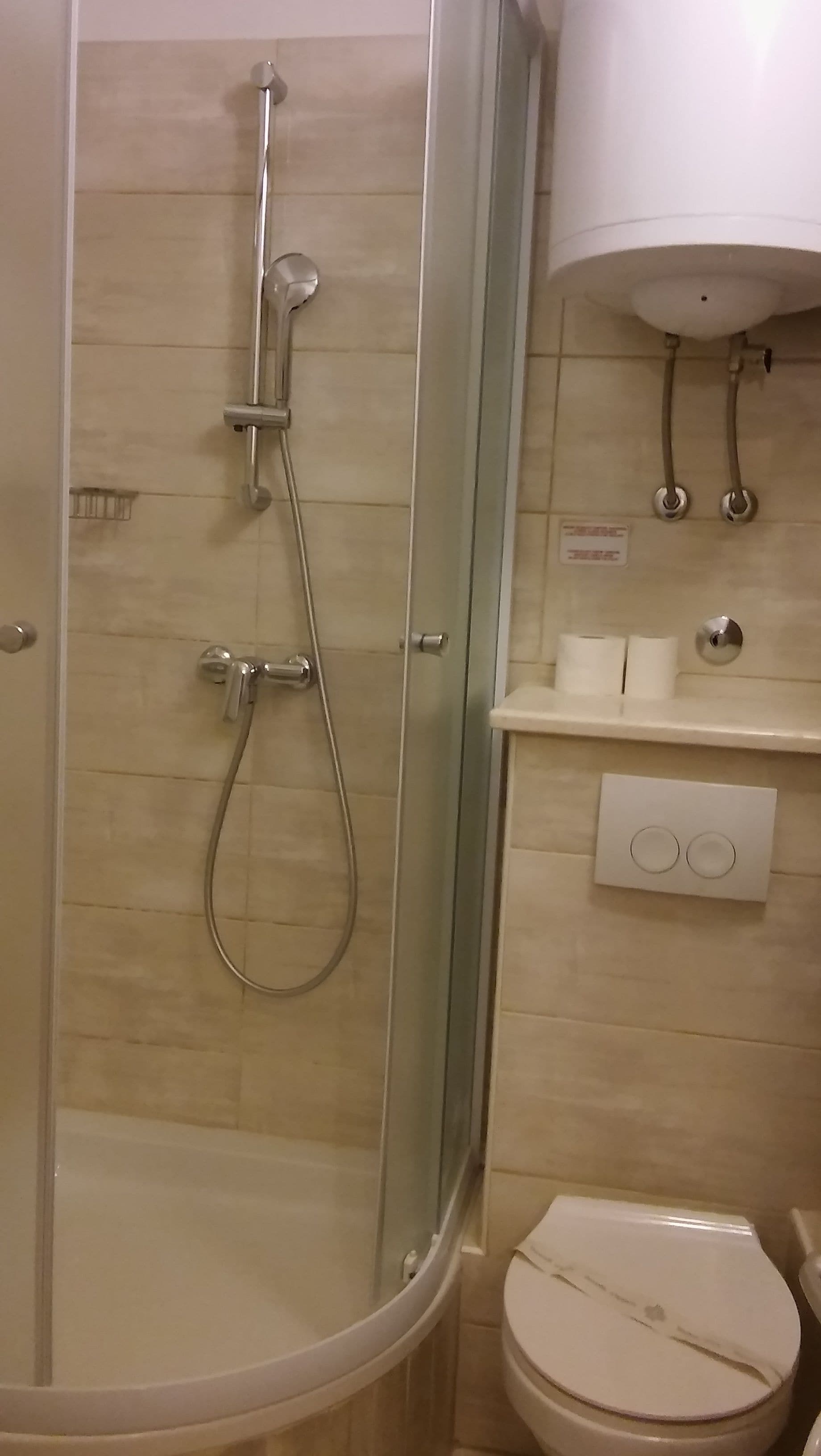 Un baño con ducha envuelta en vidrio, inodoro y lavamanos blanco.