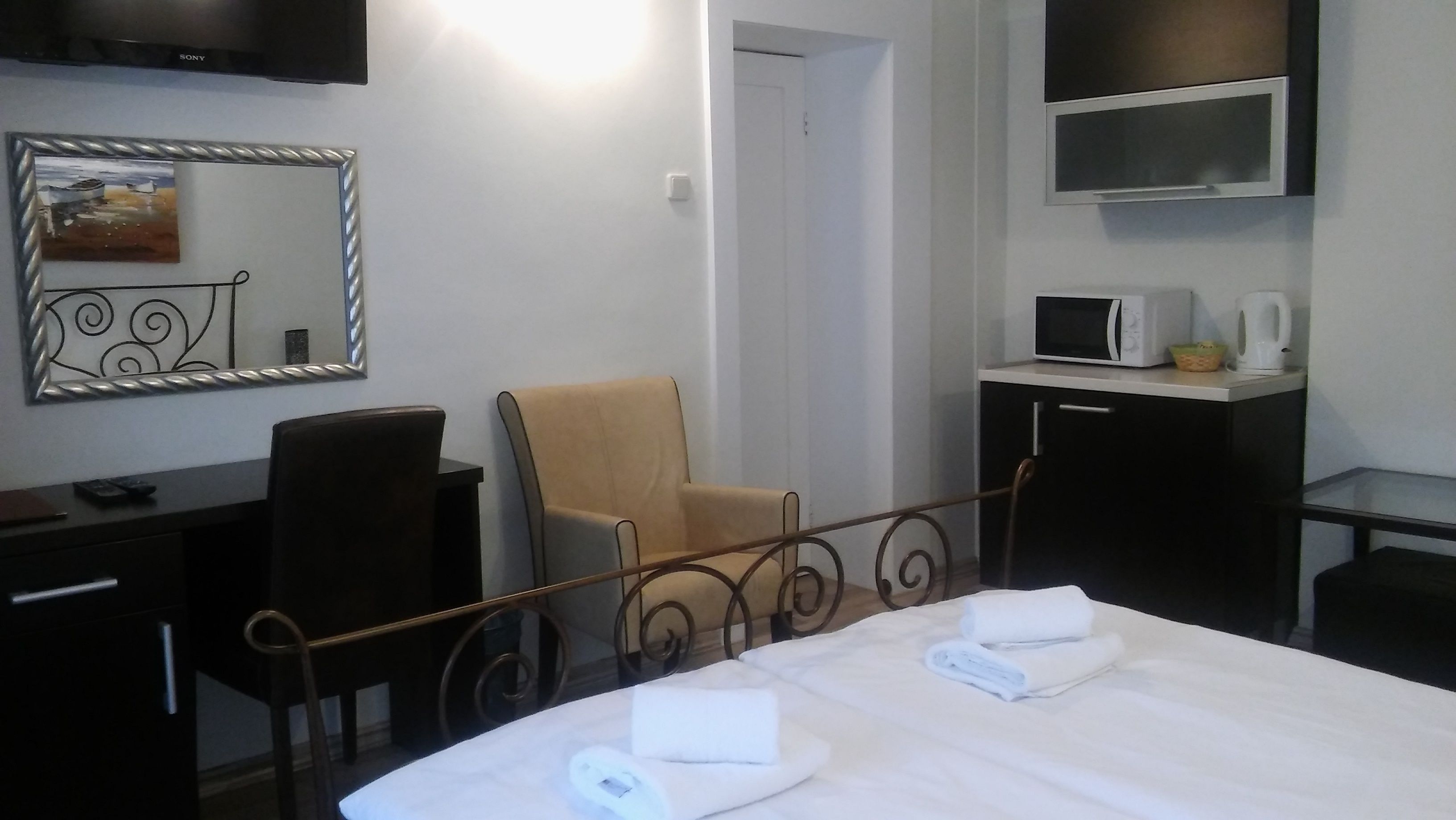 A hotel room with a bed, a desk, a chair, a TV, and a microwave.