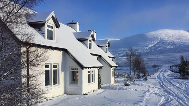 A snow-covered house with a clear sky and a mountain in the background. - Balsporran Bed And Breakfast (Dalwhinnie)