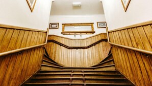 A wooden staircase with a handrail, flanked by wooden panels and framed pictures on the walls. - Balsporran Bed And Breakfast (Dalwhinnie)