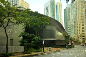 En modern byggnad med en böjd fasad, med skylten ”The Mind Museum i Taguig”.