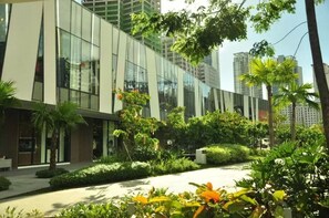 A modern building with large glass windows and a well-maintained garden with various plants and trees. - Our Awesome Hostel (Makati)