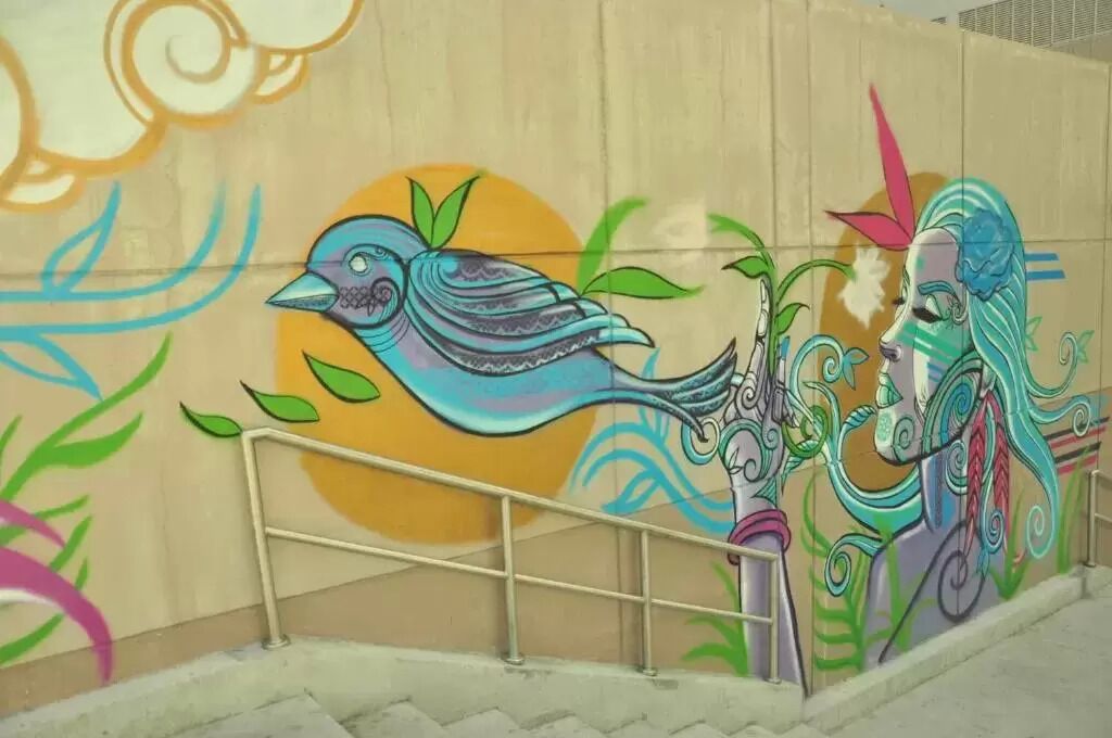 Une fresque colorée représentant un oiseau et une figure humaine sur un mur.