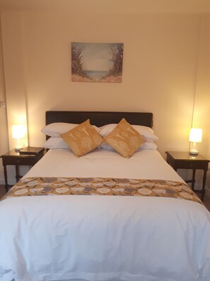 A neatly made bed with a floral-patterned bedspread and two decorative pillows, flanked by two bedside tables with lamps.