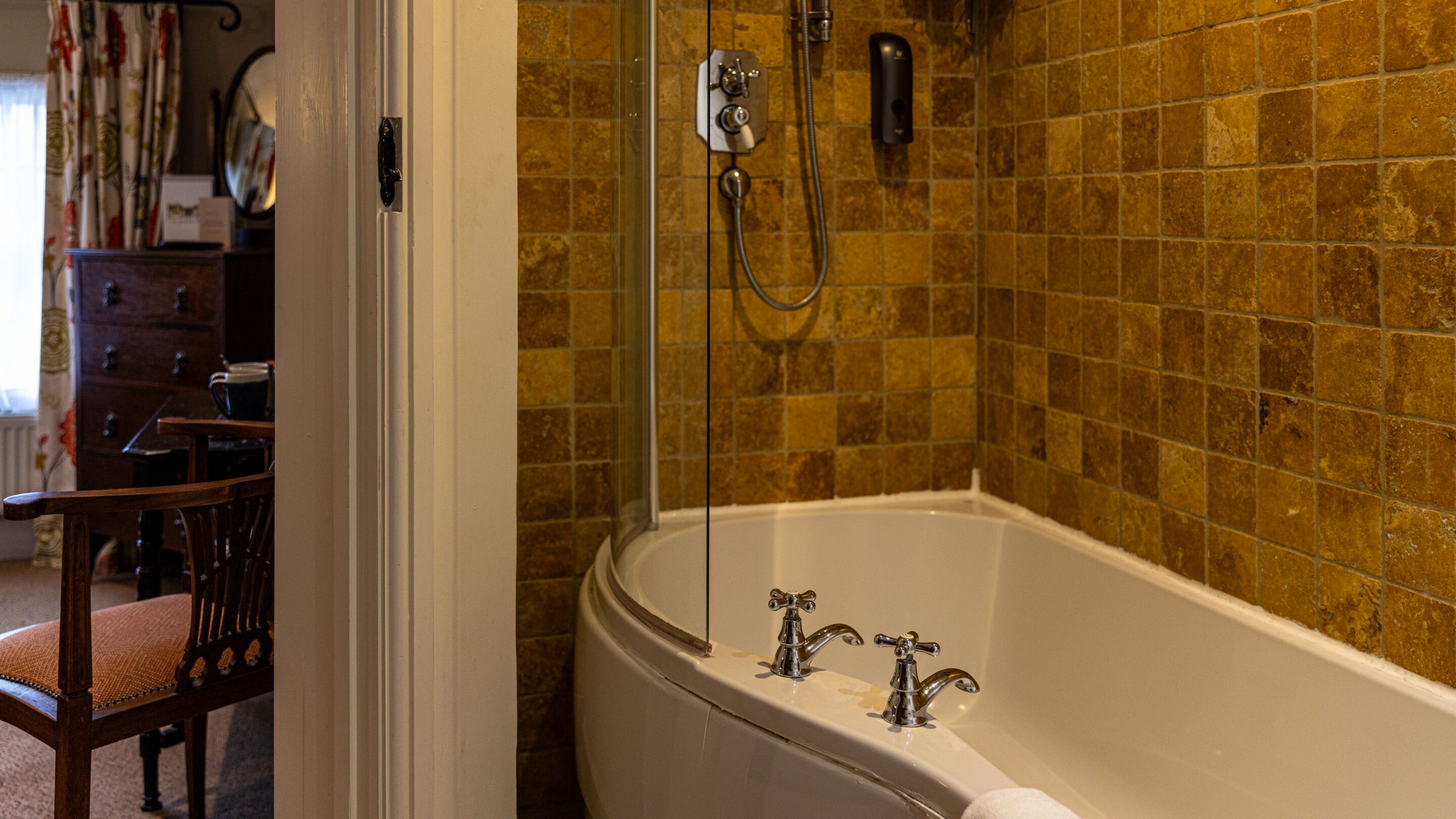 Un baño con bañera, ducha y pared con azulejos.
