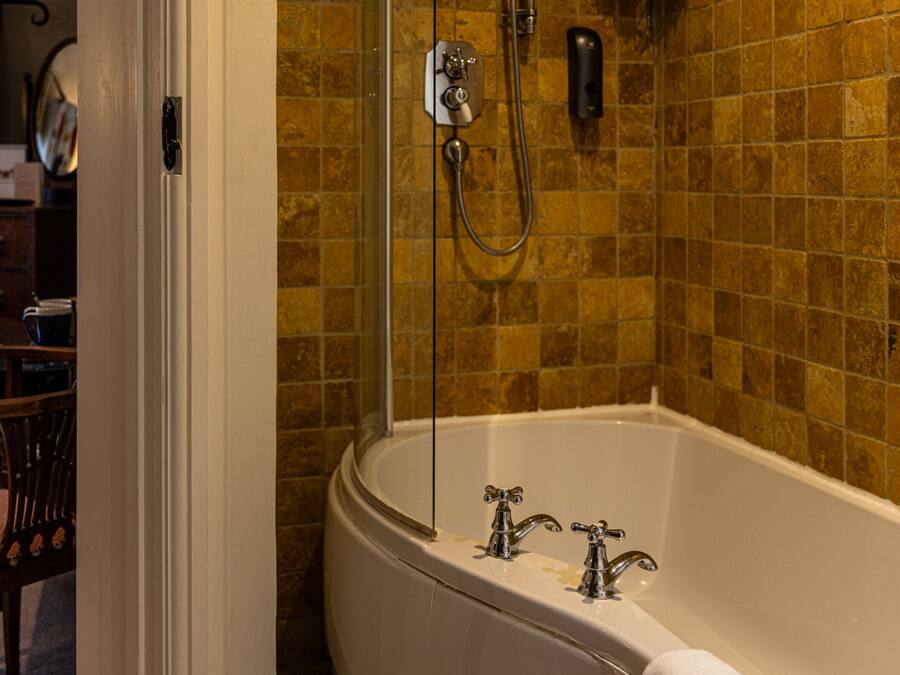 Un baño con bañera, ducha y pared con azulejos.