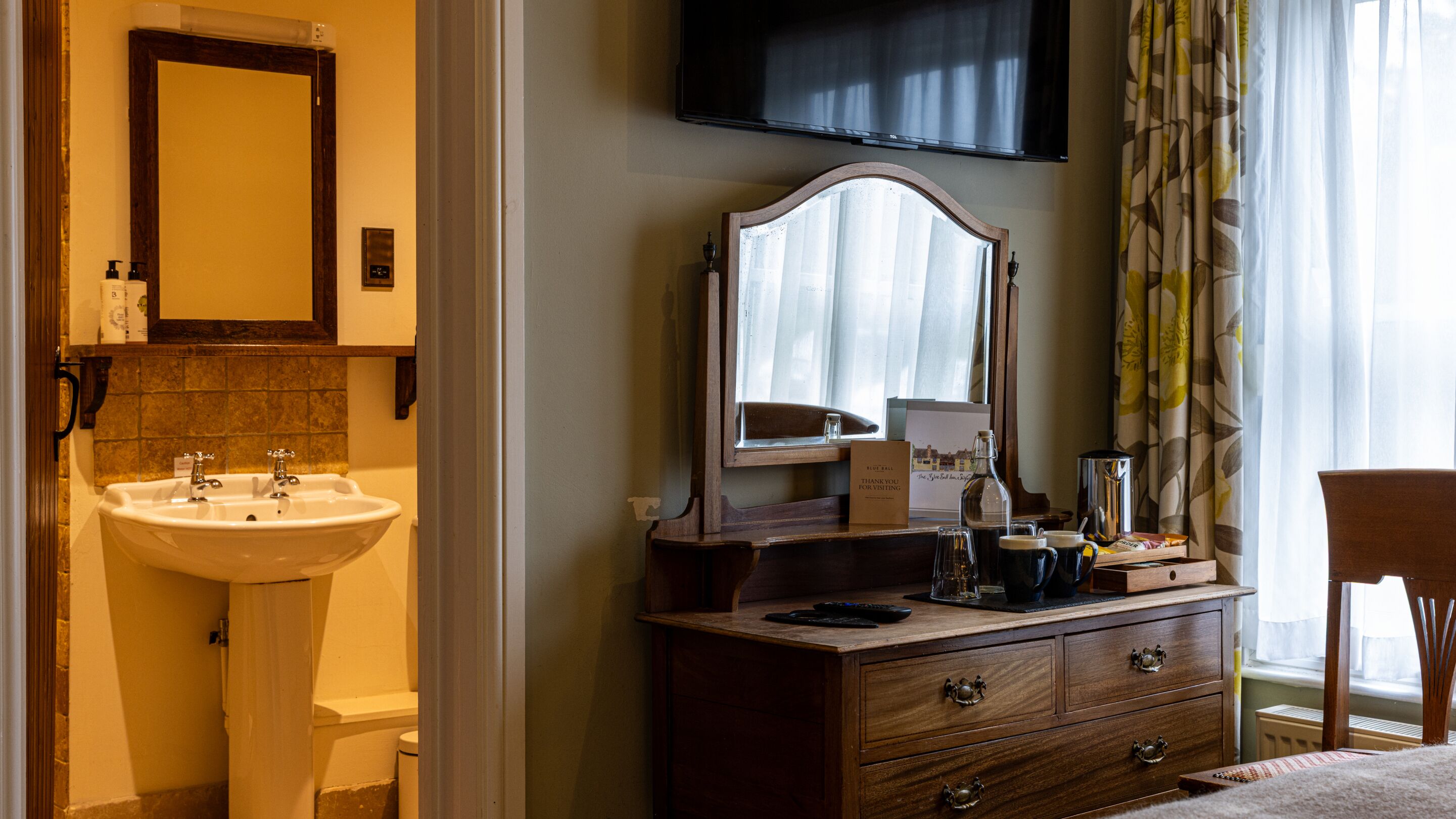 A bathroom with a sink, mirror, and toiletries.