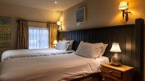 A hotel room with two beds, a nightstand with a lamp, and a painting on the wall. - Blue Ball Inn (Sidmouth)